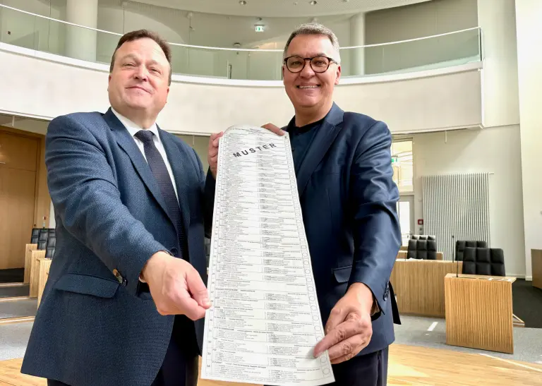 Norbert Dahmen und Thomas Westphal zeigen den Stimmzettel zur Europawahl 2024