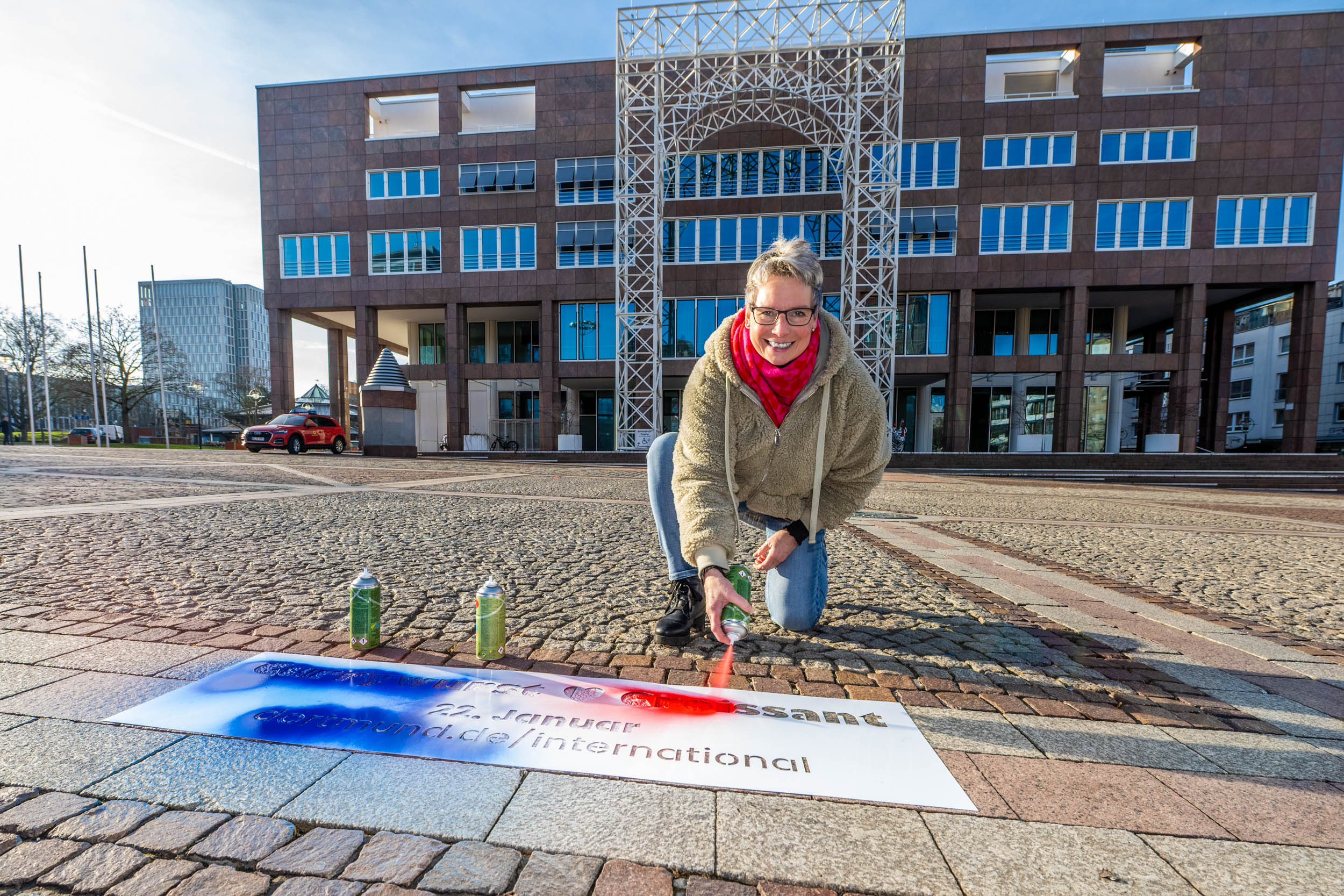 Bürgermeisterin Ute Mais sprüht anlässlich des deutsch-französischen Tages "currywurst & croissant" in der Trikolore auf den Friedensplatz