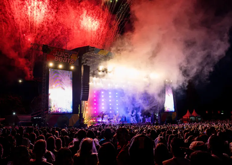 Feiernde Menschen stehen vor einer großen Bühne auf dem Juicy Beats Festival.