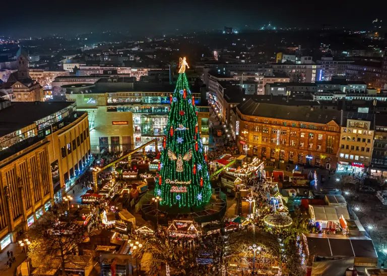 Ein Blick von oben auf die erleuchtete Dortmunder Weihnachtsstadt bei Nacht, im Zentrum steht der Weihnachtsbaum.