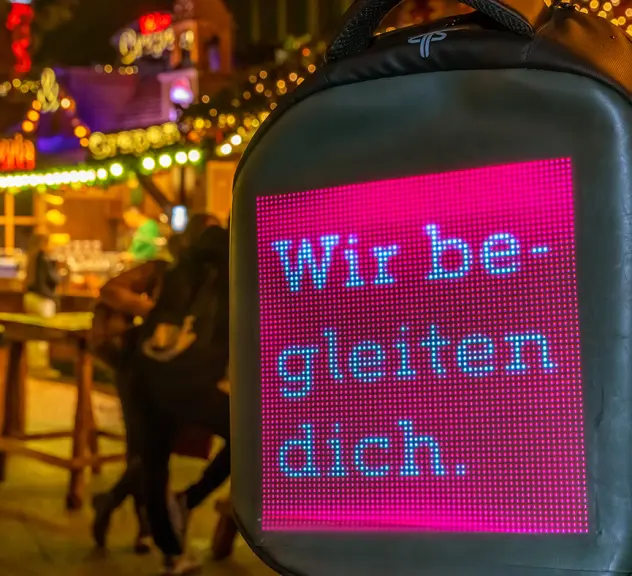 Ein Rucksack mit LED-Schrift "Wir begleiten dich", getragen von einem der Dortmund Guides.