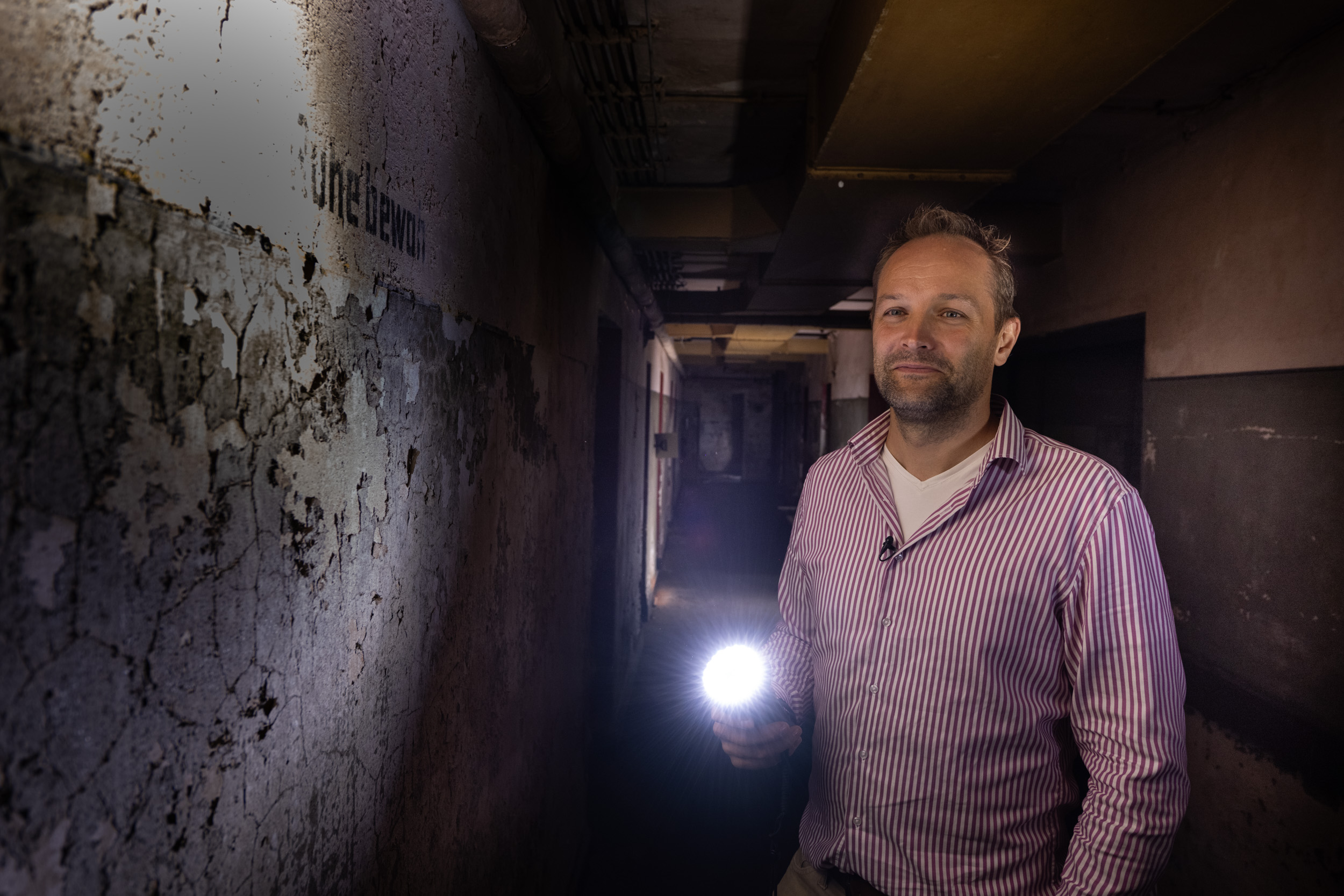 Stadtarchäologe Ingmar Luther steht im Bunker mit einer eingeschalteten Taschenlampe.