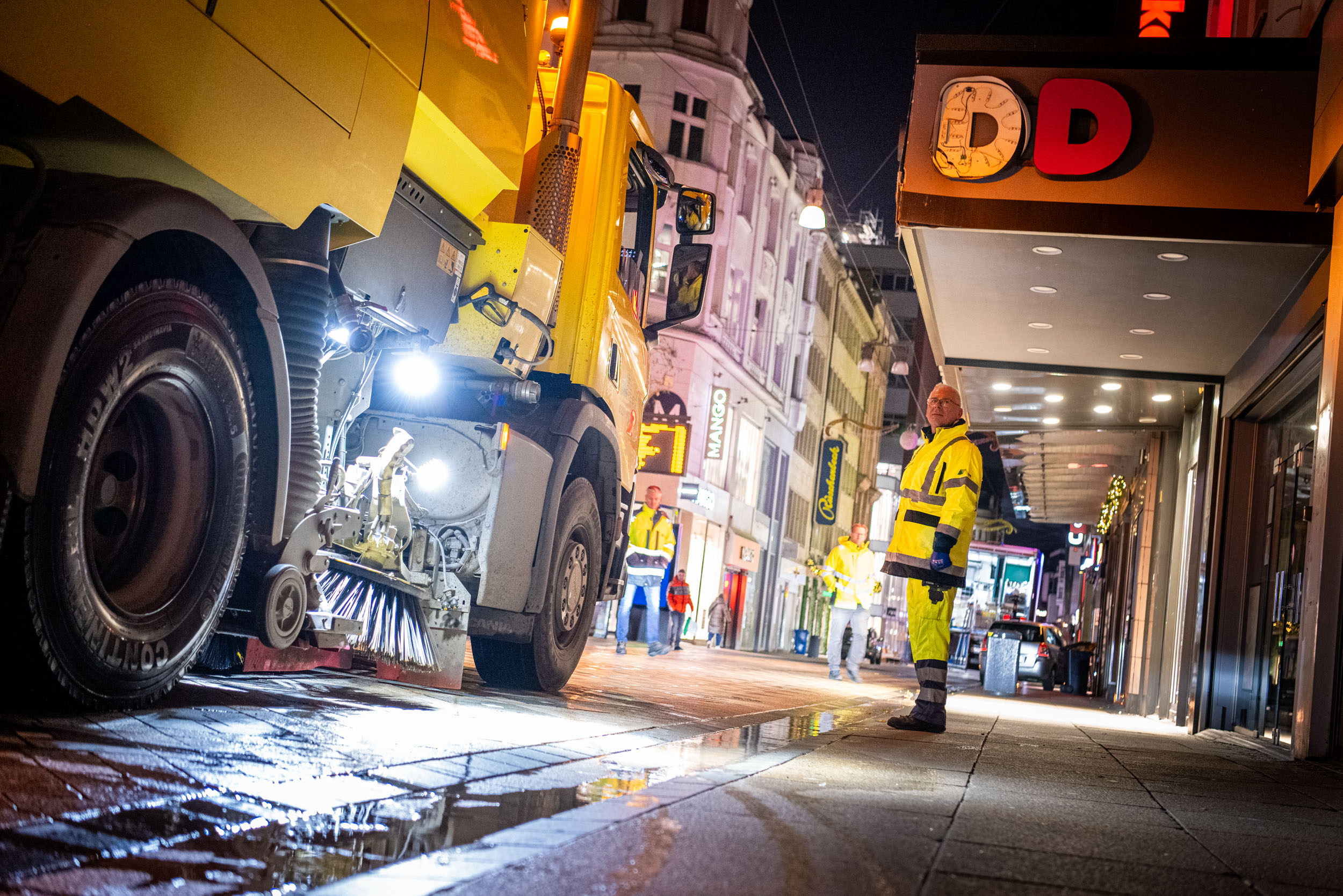 Mitarbeiter der EDG stehen neben einem Reinigungsfahrzeug bereit, händisch nachzuarbeiten.
