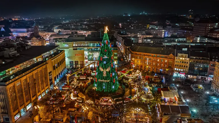 Ein Blick von oben auf die erleuchtete Dortmunder Weihnachtsstadt bei Nacht, im Zentrum steht der Weihnachtsbaum.
