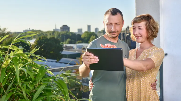 Paar schaut sich etwas auf einem Tablet an. Im Hintergrund sieht man die Dortmunder Skyline
