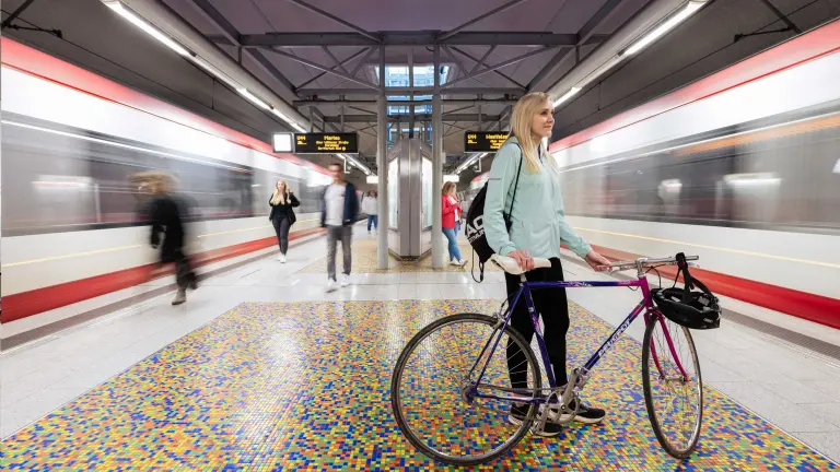 Person mit Fahrrad an einer U-Bahn-Haltestelle in Dortmund mit einfahrenden U-Bahnen rechts und links
