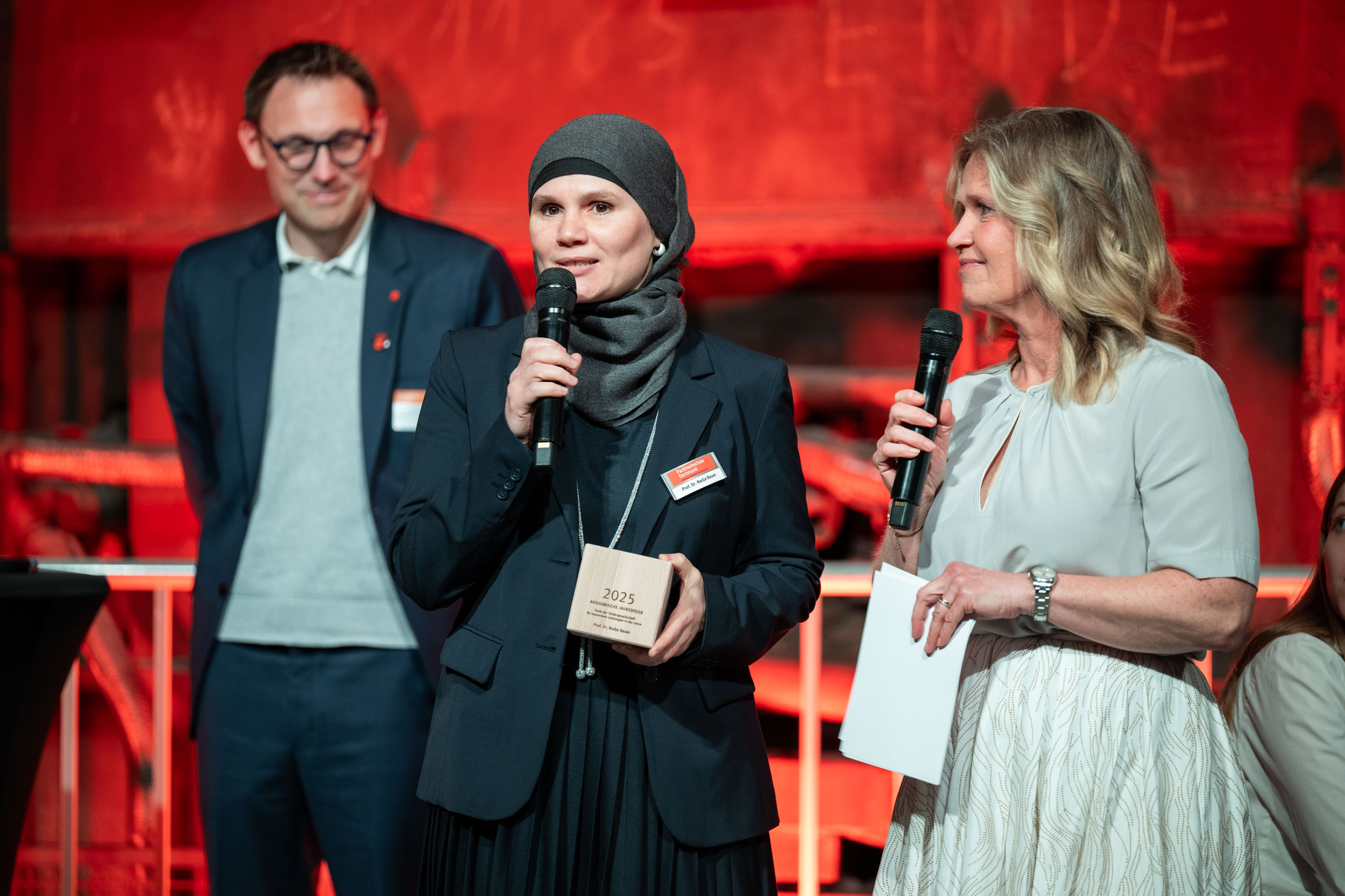 Drei Menschen auf einer Bühne.