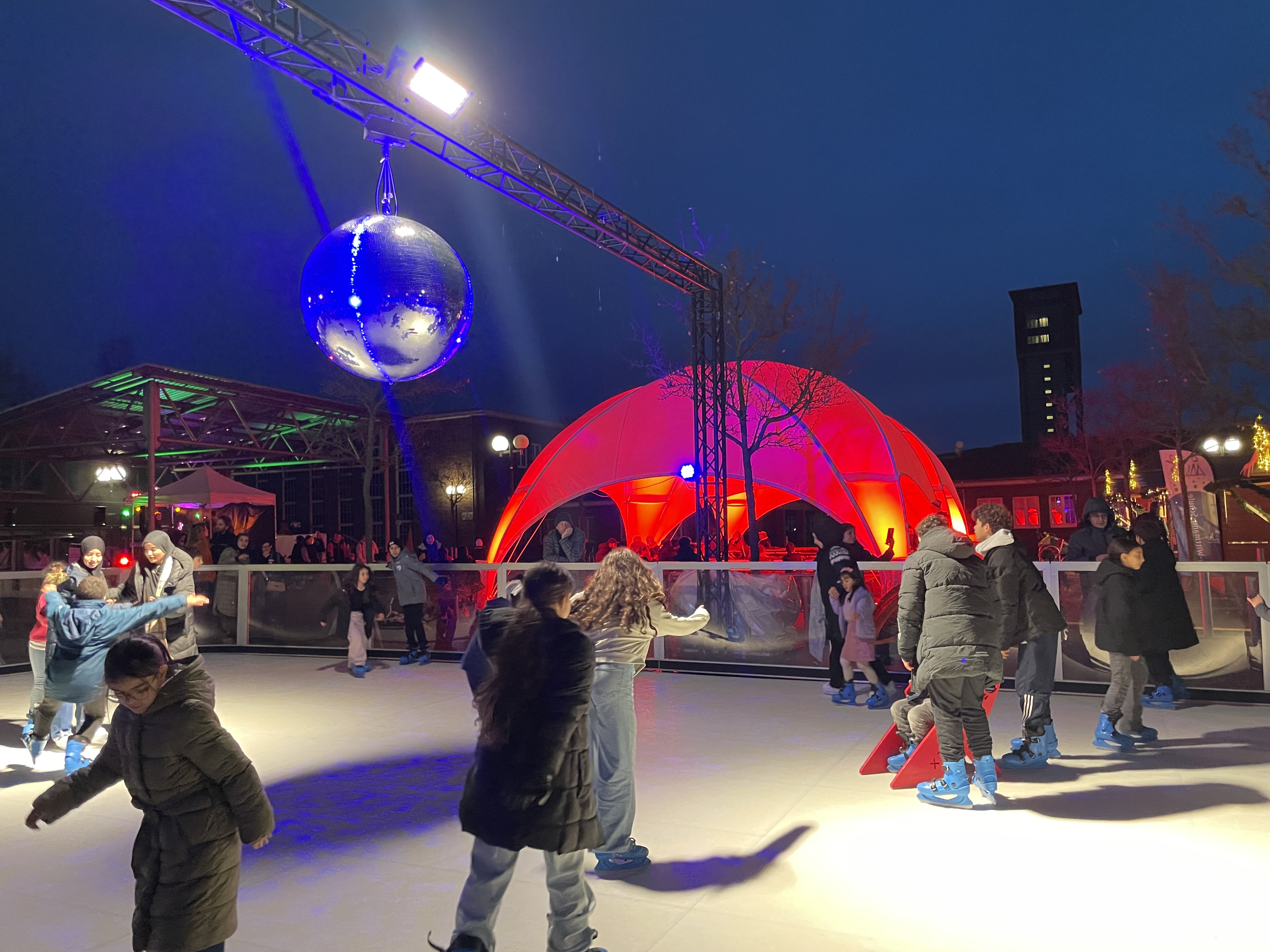 Kinder fahren Schlittschuh auf einer Eisbahn im Freien.
