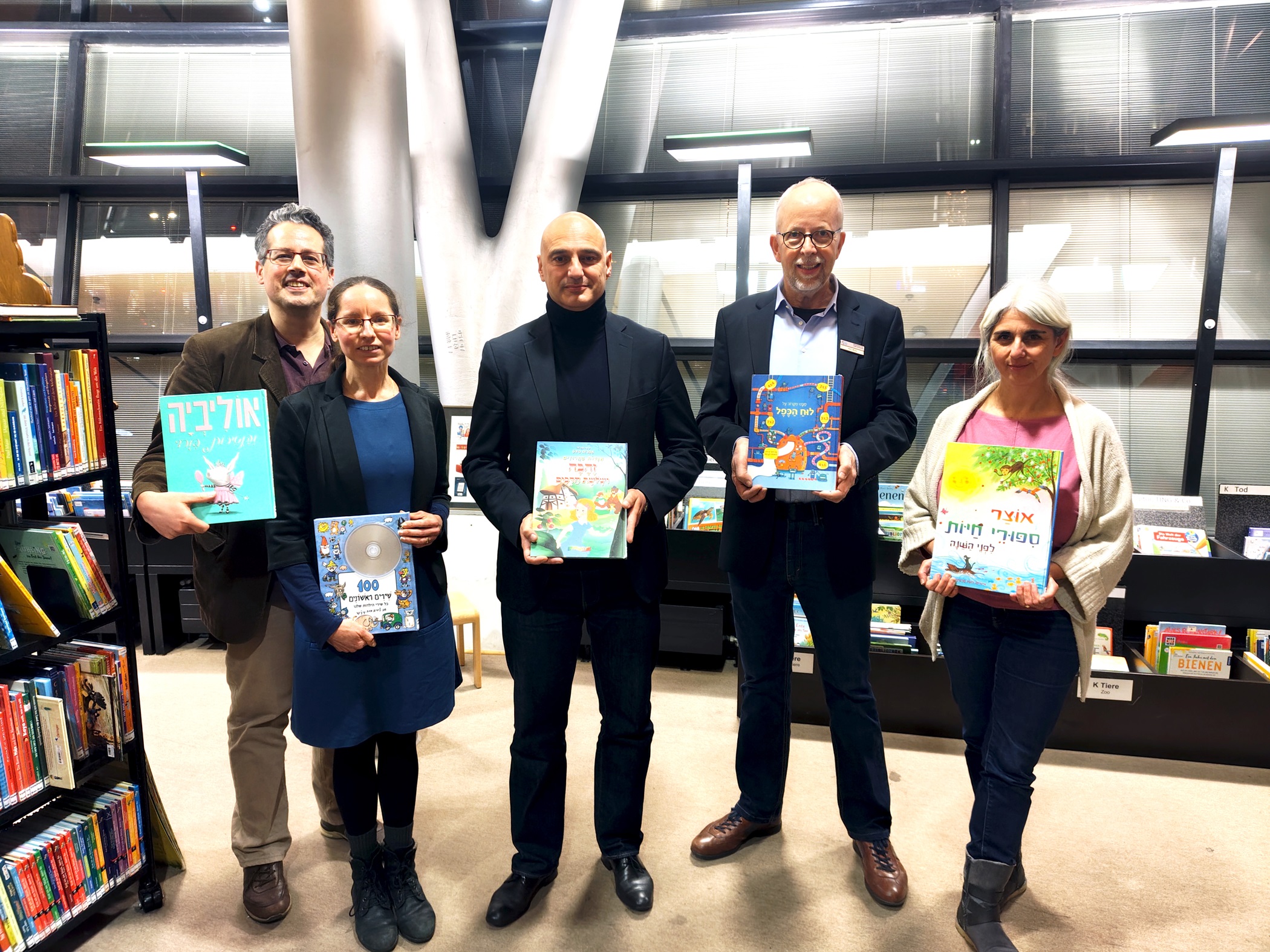 Vier Menschen stehen nebeneinander und halten je ein Buch.