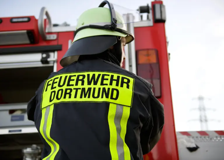 Rückansicht einer Person in Feuerwehr-Dienstkleidung mit der Aufschrift "Feuerwehr Dortmund"
