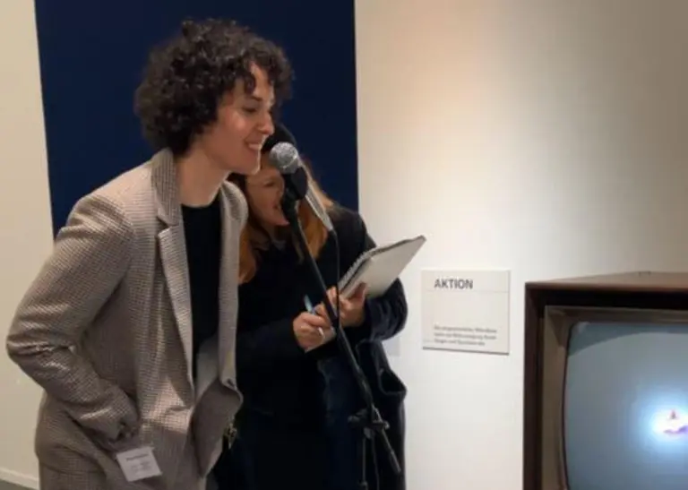 Die Kuratorin Christina Danick zeigt, wie die Kunstwerke in der Ausstellung "Nam June Paik: I Expose the Music" aktiviert werden können. Hier spricht sie in ein Mikrofon. Die Frequenz ihrer Stimme wird auf einem Fernsehbildschirm visualisiert.