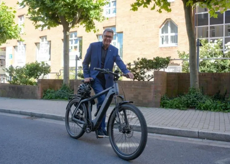 Oberbürgermeister Thomas Westphal steht an der Straßenseite und hält ein Fahrrad am Lenkrad fest