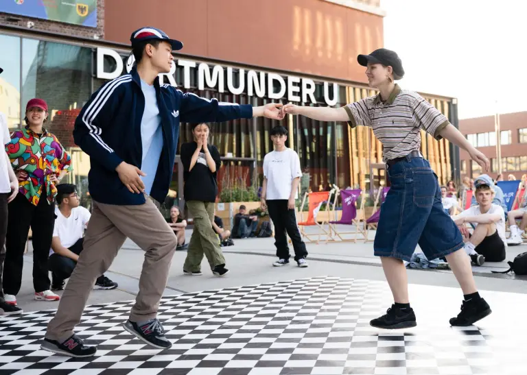 Menschen tanzen auf einer Tanzfläche vor dem Haupteingang des Dortmunder U