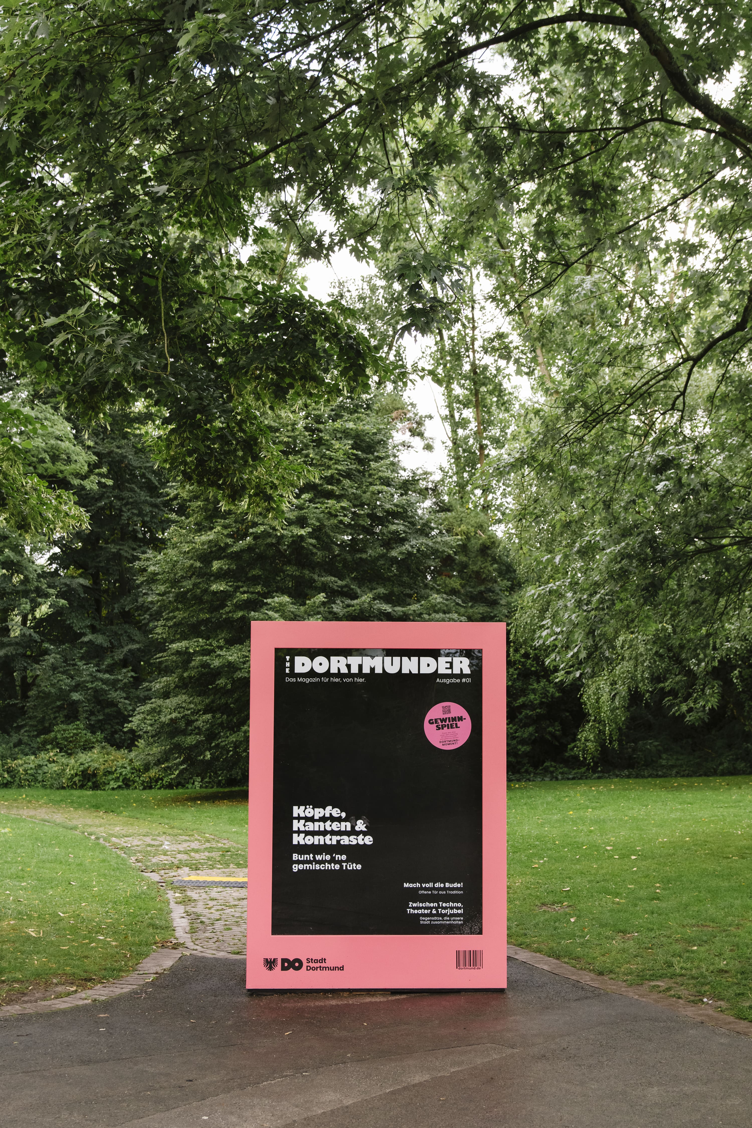 Ein begehbares Magazincover steht in einem Park