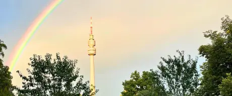 Ein beeindruckender Regenbogen spannt sich über den Westfalenpark in Dortmund mit Blick auf den Fernsehturm, umgeben von üppigem Grün und gepflegten Wegen, symbolisiert ein perfektes Ausflugsziel für Natur- und Freizeitliebhaber.*innen