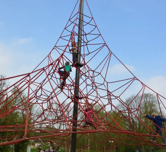 Kinder erklimmen eine Kletterspinne auf einem der Spielplätze im Westfalenpark, eine beliebte Attraktion, die Mut und Geschicklichkeit fördert