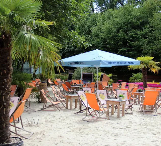 Stadtstrand im Westfalenpark Dortmund mit Liegestühlen, Sonnenschirmen und Palmen, ein sommerliches Flair mitten in der Stadt.