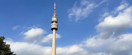 Der Florianturm im Westfalenpark Dortmund, eingefangen gegen einen dynamischen Himmel mit Wolken, bietet ein markantes Bild des modernen Dortmund, umrahmt von der natürlichen Schönheit des Parks.