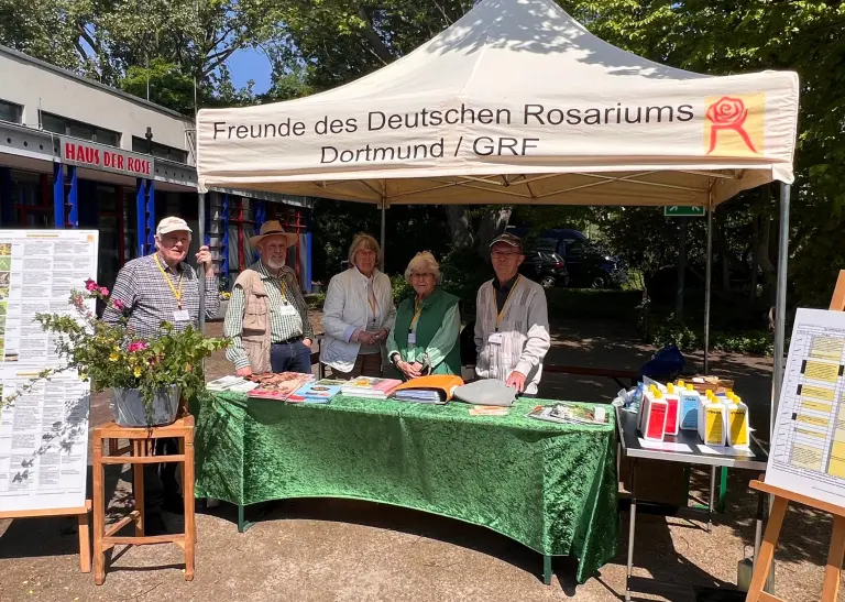 Engagierte Mitglieder des Fördervereins Deutsches Rosarium Dortmund stehen am Informationsstand vor dem Haus der Rose im Westfalenpark, bereit, Besucher*innen über die Schönheit der Rosen und die Aktivitäten des Vereins zu informieren.