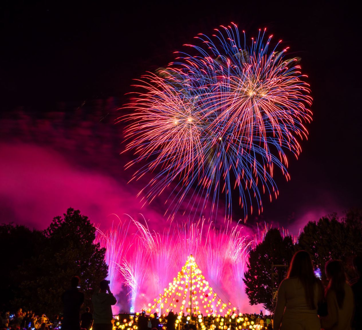 Spektakuläres Feuerwerk über dem Westfalenpark während des Lichterfests mit einem traditionellen Lichterbaum im Vordergrund und begeisterten Zuschauer*innen