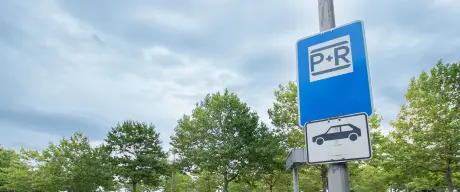 P+R Schild auf einem Parkplatz in Dortmund mit parkenden Autos im Hintergrund.