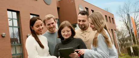 Mehrere Studierende schauen auf ein Tablet