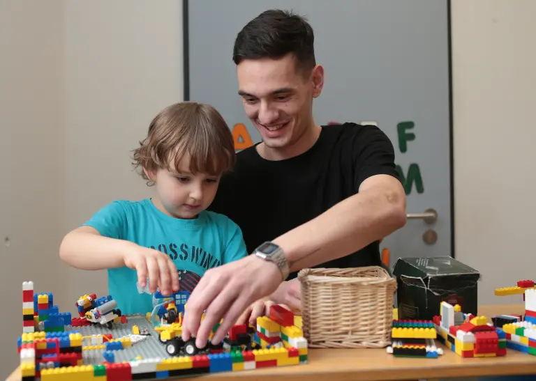 Eine Person spielt mit einem Kind Lego