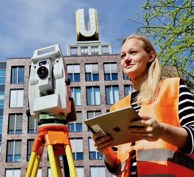 Eine Person steht mit einem Vermessungsgerät und einem IPad in der Hand unten auf dem Platz vor dem Dortmunder U