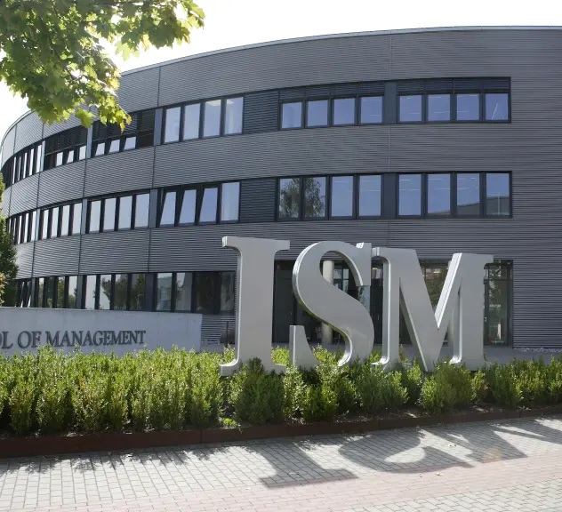 Gebäude der International School of Management im Hintergrund. Im Vordergrund große ISM Skulptur in grau. 