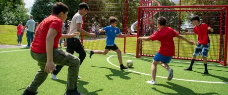 Eine Gruppe Kinder spielt auf einer Wiese Fußball.