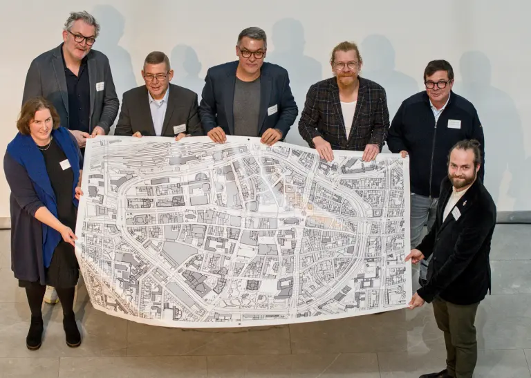 Verschiedene Akteur*innen halten einen großen Stadtplan der Dortmunder City in den Händen.