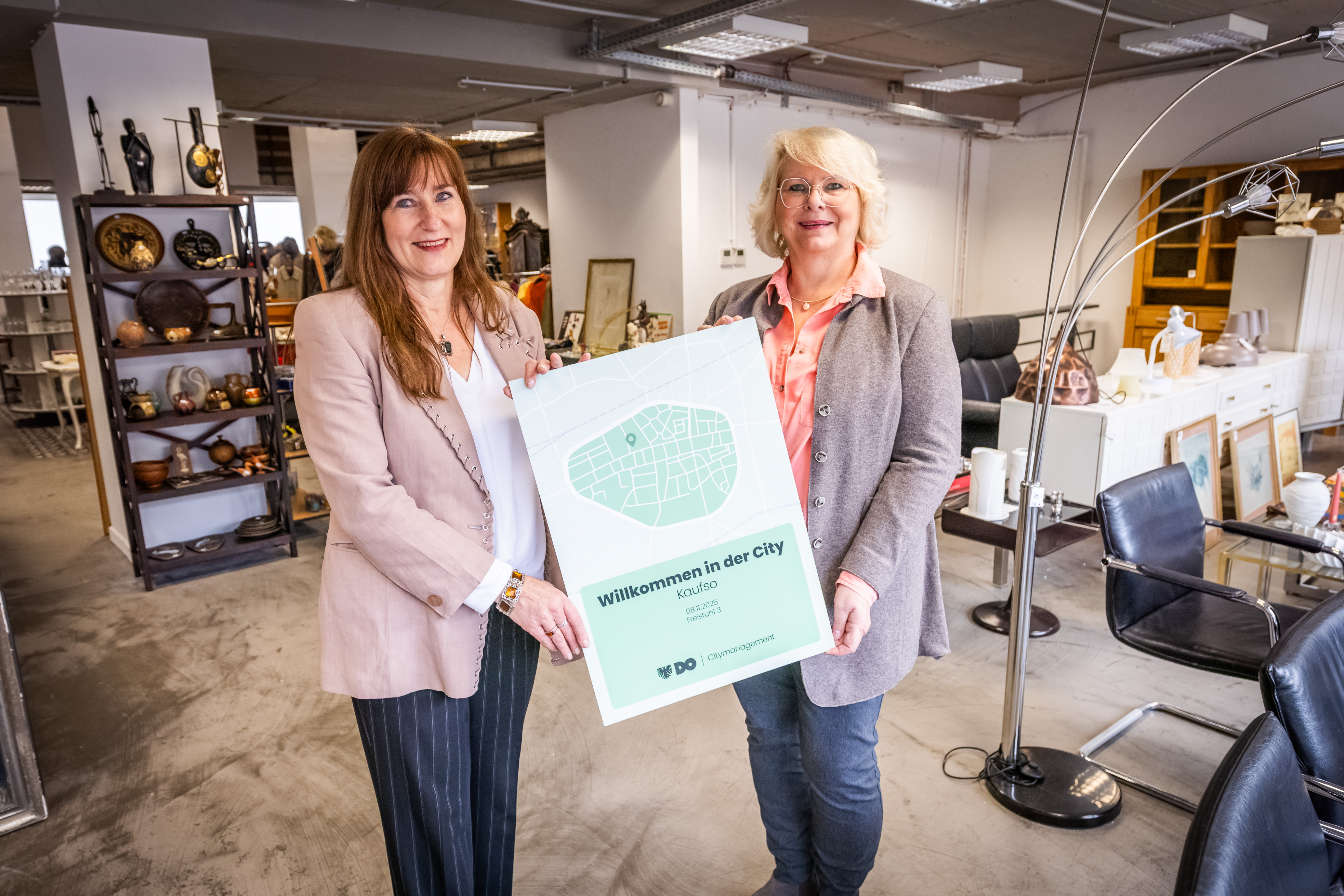 Zwei Frauen in einem Einrichtungsgeschäft halten eine stilisierte Karte der Dortmunder City in die Kamera.
