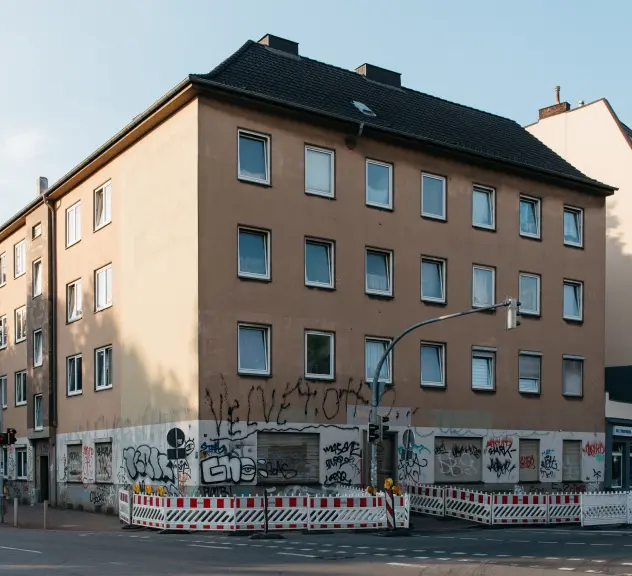 Ein Haus voller Graffiti mit einem Bauzaun im Vordergrund