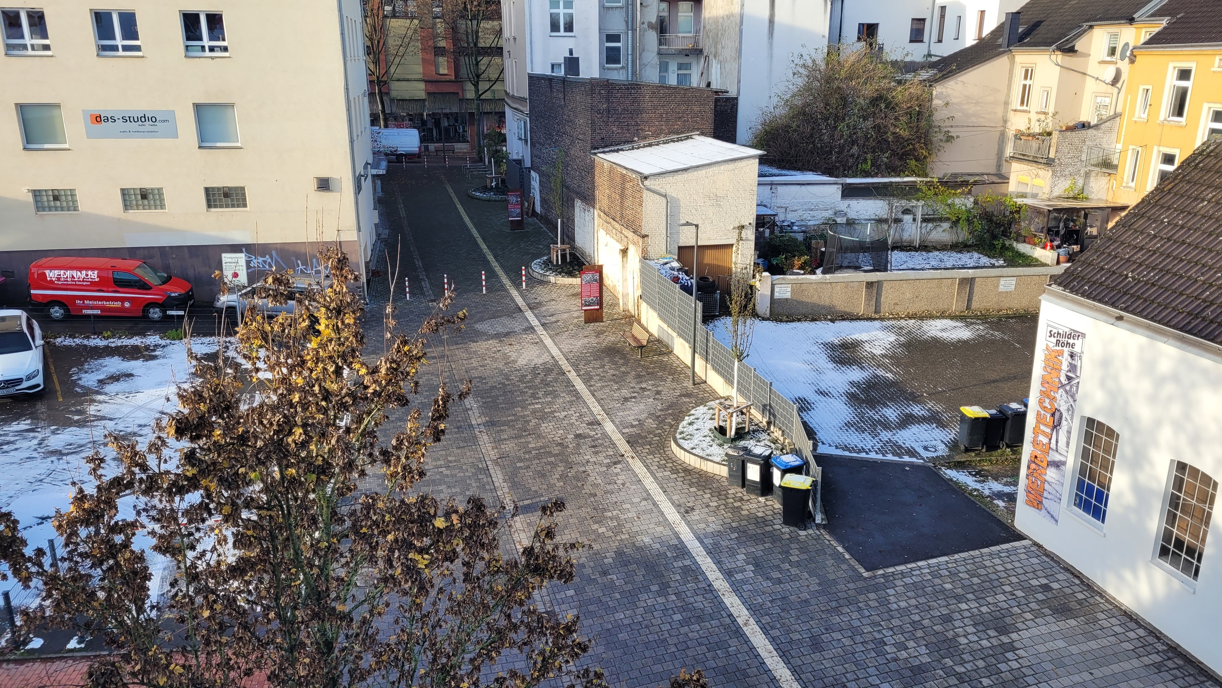 Foto aus der Vogelperspektive einer neu gepflasterten Fläche mit taktilem Leitsystem, neu gepflanzten Bäumen und Infostelen.