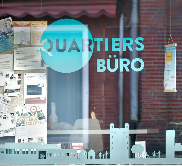 Foto eines Schaufensters mit verschiedenen Plakaten und der Aufschrift "Quartiersbüro"