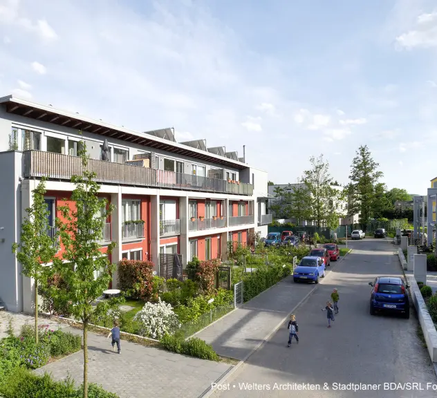 Wohngebiet in Dortmund. Eine Straße führt durch Mehrfamilienhäuser, Autos stehen geparkt und Kinder laufen über die Straße.