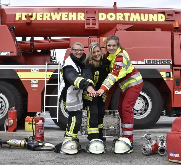 Drei Frauen in Feuerwehr-Kluft vor einem Dortmunder Feuerwehrauto