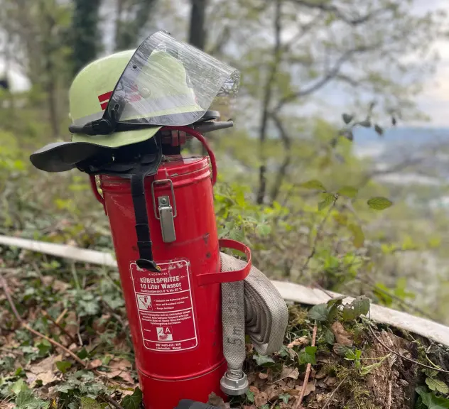 Löschgerät und Feuerwehrhelm in einem Wald