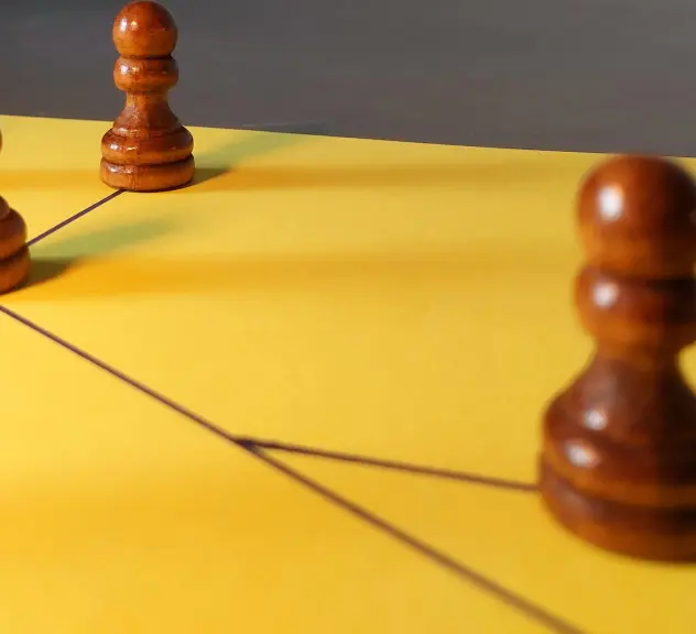 Holz-Spielfiguren auf einem gelben Spielfeld mit netzähnlichen schwarzen Linien