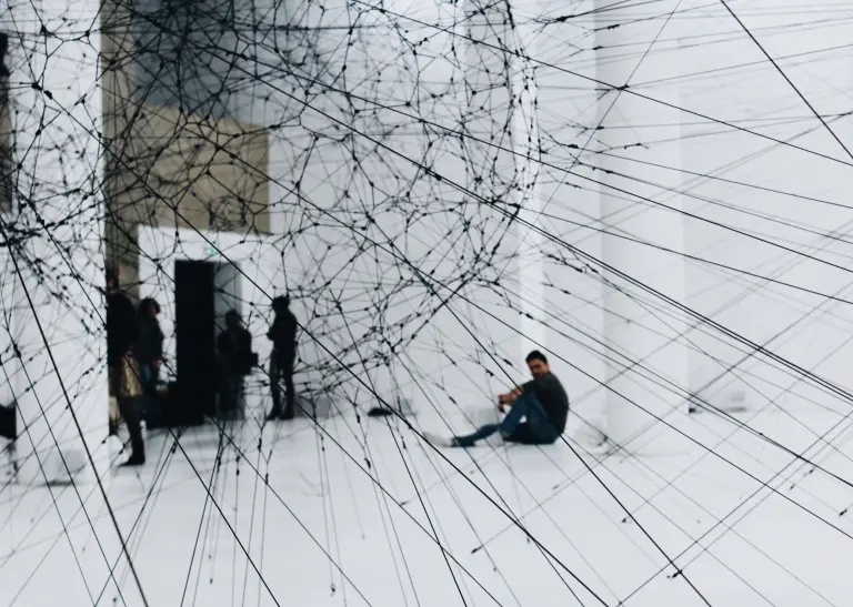 Eine Halle mit Netzen aus Stoff. Durch das Netz schauend sieht man verschiedene Menschen.