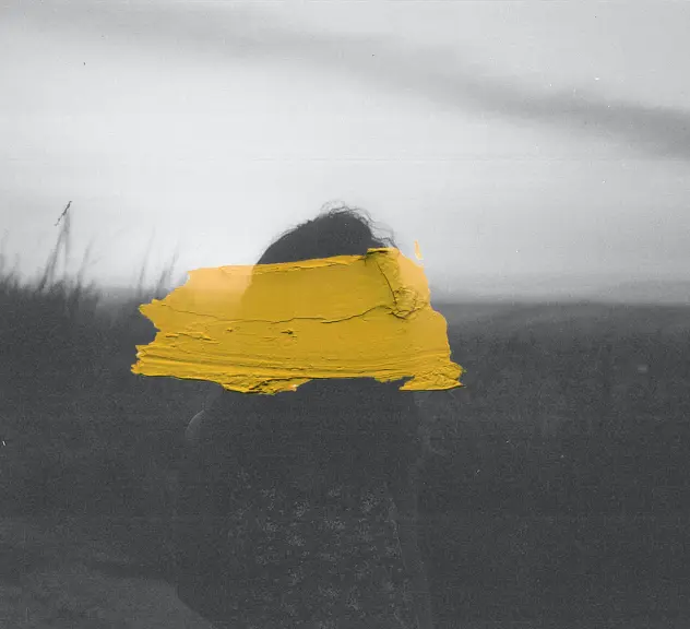 Eine Fotographie einer Frau auf einer Düne befleckt mit einem gelben Farbstrich. 