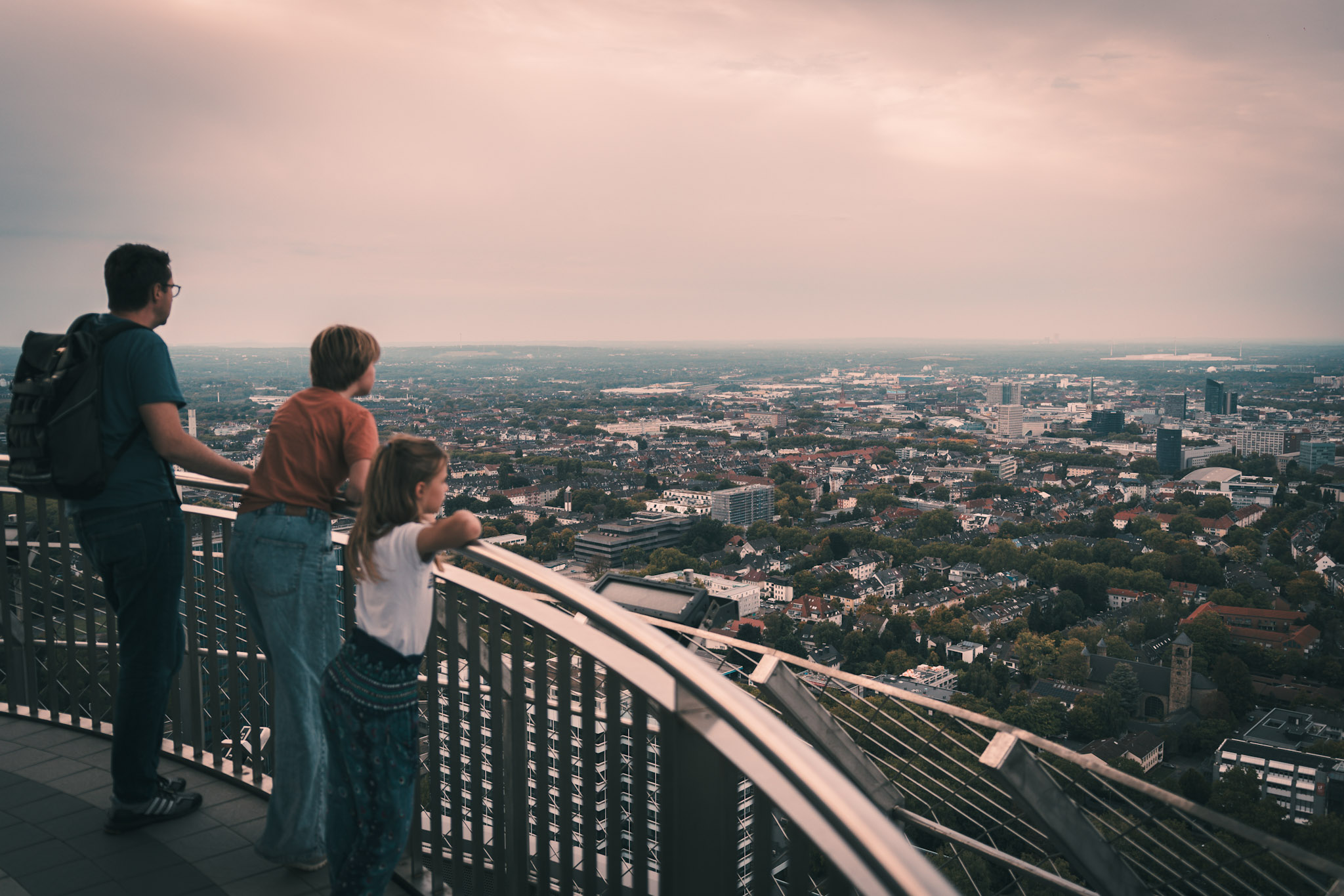 Drei Personen, die den Ausblick über Dortmund auf der Aussichtsplattform des Florianturms im Westfalenpark genießen.