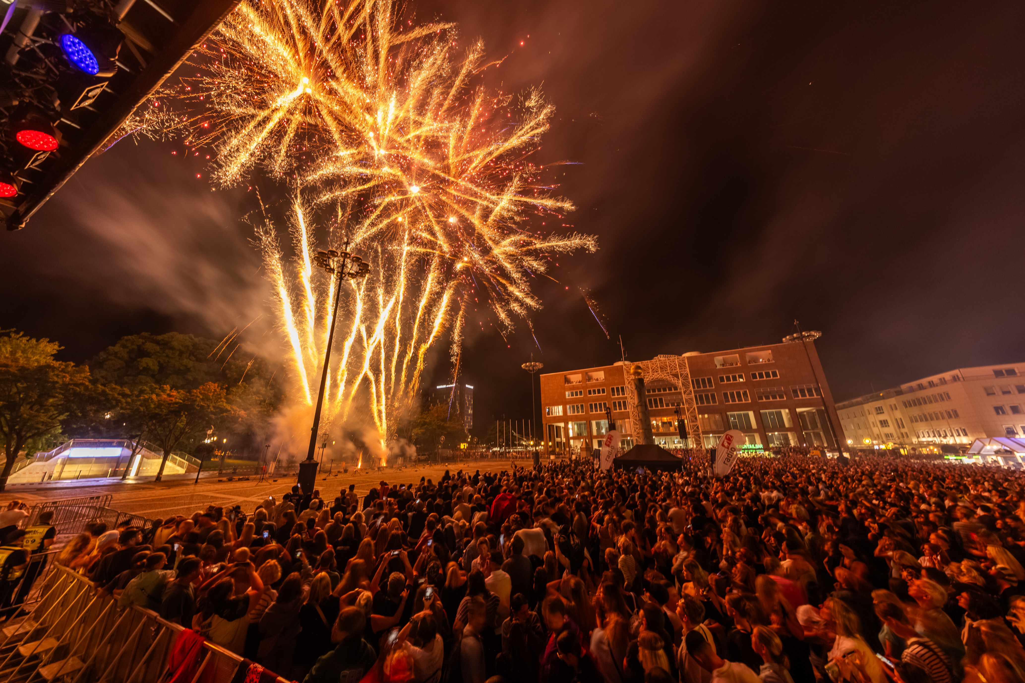 Bodenfeuerwerk auf dem Friedensplatz. Im Hintergrund ist das Rathaus zu sehen, der Friedensplatz ist gefüllt mit Menschen.