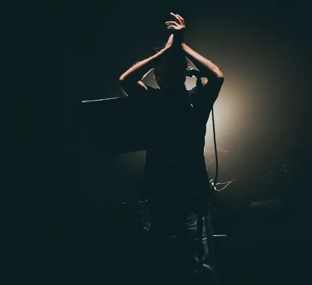 Ein Mann klatschend im dunkel auf der Bühne. 