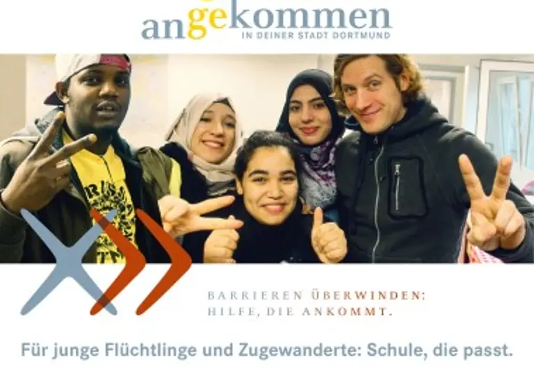 Foto von einem Lehrer und vier Jugendlichen, die lächelnd ein Peace-Handzeichen in die Kamera zeigen.