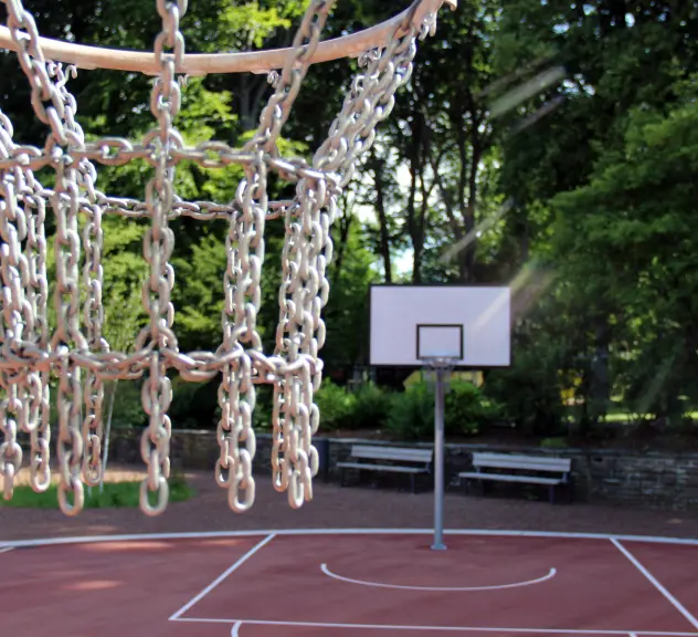 Das Netz eines Basketballkorbs, im Hintergrund der gegenüber liegende Baskettballkorb.