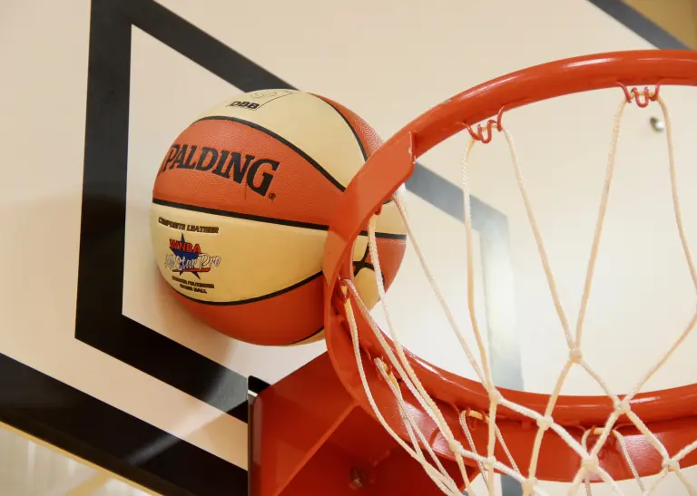 Ein Basketball steckt zwischen Basketballkorb und der Rückwand fest.