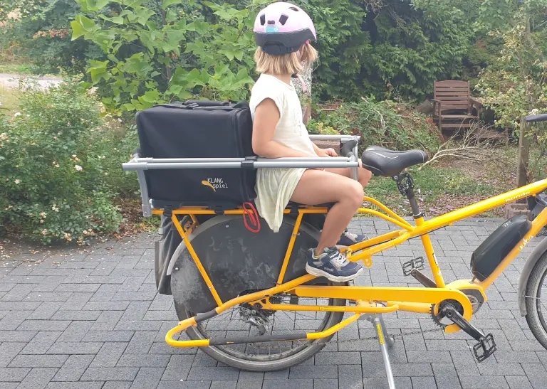 Ein Kind auf einem Lastenrad, das in einem Garten steht