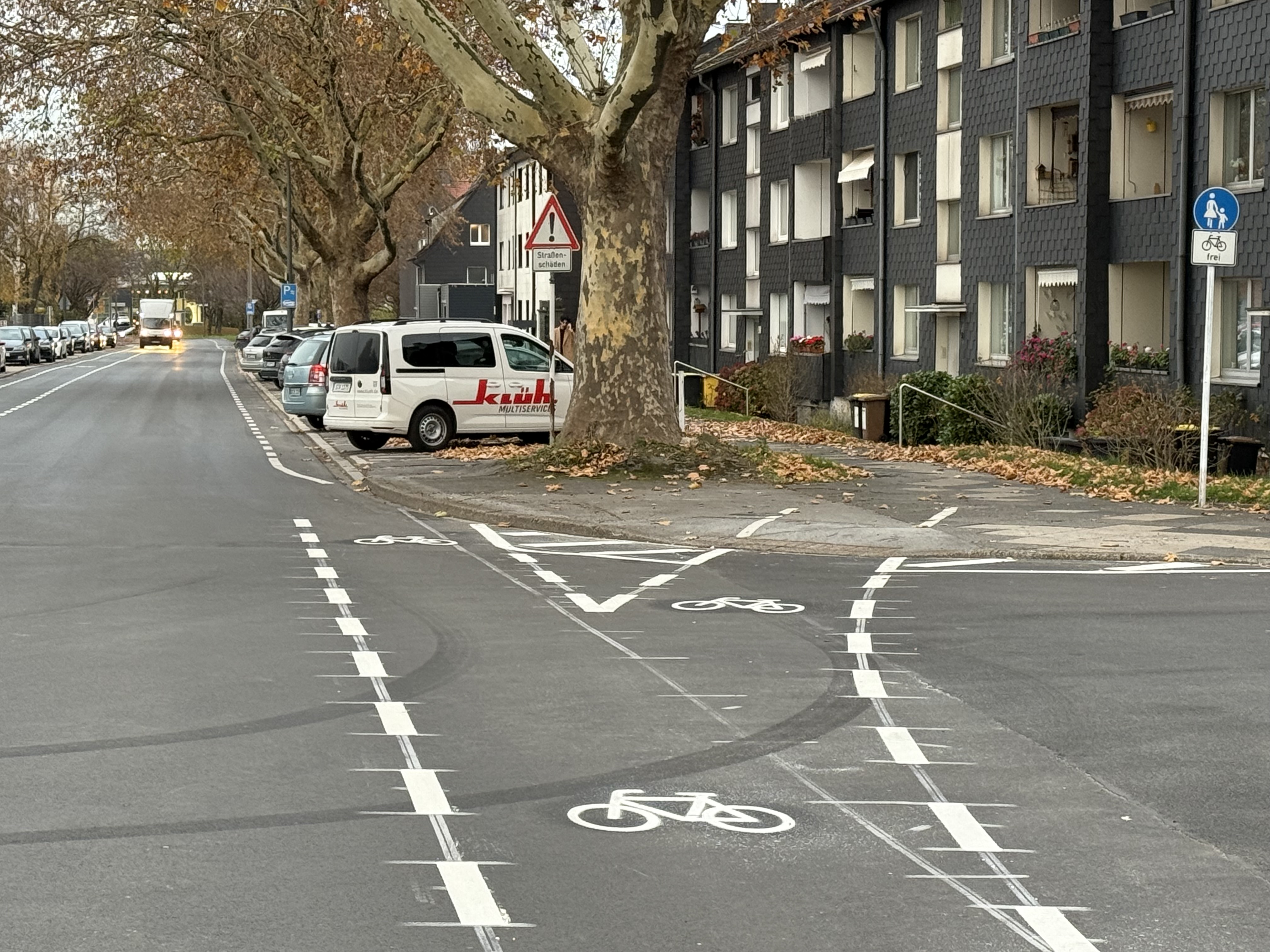 Markierte Fahrradweiche auf einer Straße. Die Furt, die nach rechts abknickt führt auf einen Gehweg, der für den Radverkehr freigegeben ist. Die linke Furt führt auf die Fahrbahn und in den Mischverkehr. 