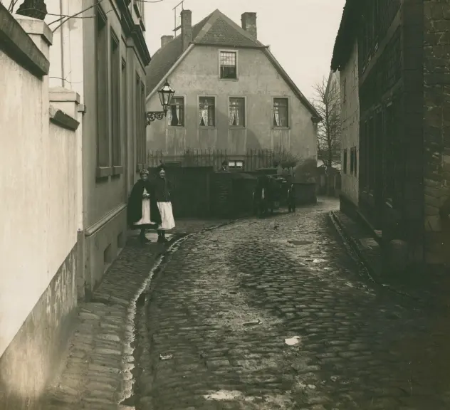 Eisenmarkt 1 vor 1918, zwei Kinder stehen links auf dem Bürgersteig im Hintergrund ist ein Pferd mit Kutsche zu sehen